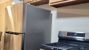 Une cuisine équipée d’un réfrigérateur en acier inoxydable, d’une cuisinière à gaz, de meubles de rangement en bois et d’un four à micro-ondes.