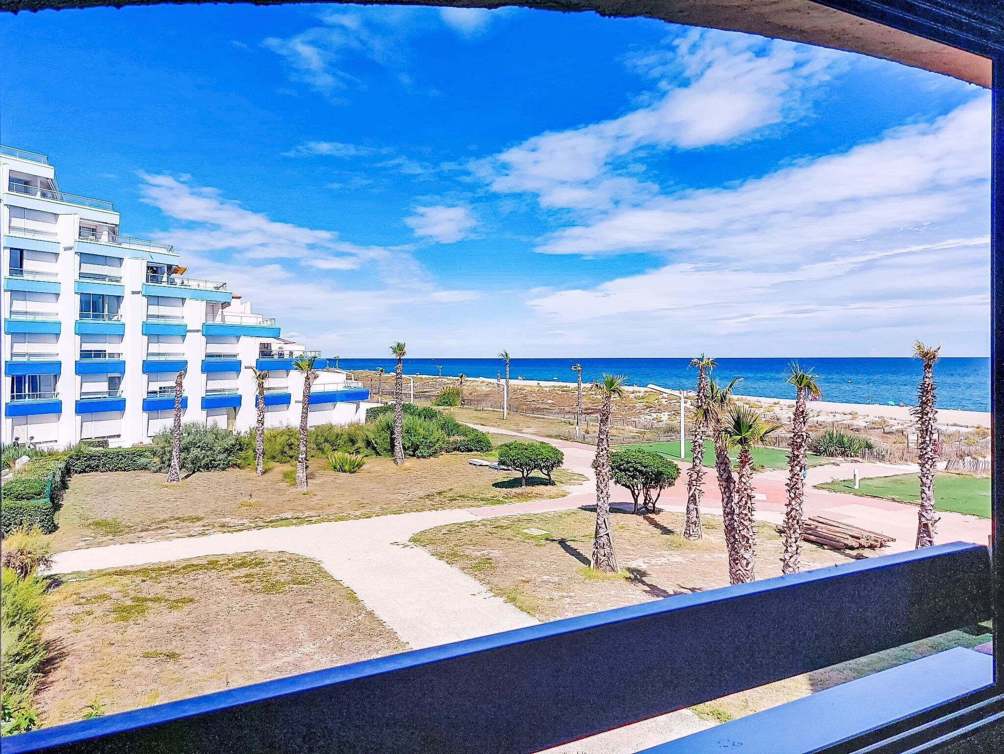 Un hotel sulla costa con diverse altezze, vista sulla spiaggia e palme.