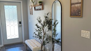 Un pasillo con un banco, un espejo grande y una planta en maceta.