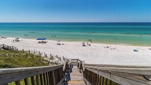 A wooden boardwalk leading to a beach with umbrellas and people. - Private Beach Access + Bikes | Quiet Family Cottage Near Alys (Inlet Beach)