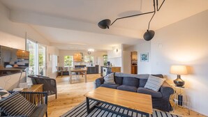 A modern living room with a sofa, coffee table, and dining area. - Beach Cottage w/ Water Access (Port Ludlow)