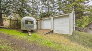 A small, single-story building with a garage and a covered outdoor area. - Beach Cottage w/ Water Access (Port Ludlow)