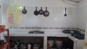 Una cocina con azulejos blancos, un lavabo y ollas colgantes.