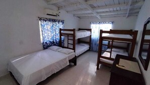 Una habitación con literas, un escritorio pequeño y una ventana con cortinas.