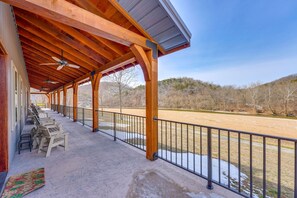 A covered outdoor seating area with chairs and a view of a river.