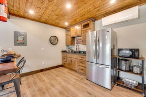 Une cuisine avec des meubles en bois, un réfrigérateur en acier inoxydable, un four à micro-ondes et un grille-pain.