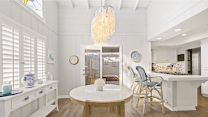 A kitchen with white cabinetry, a round dining table, wicker chairs, and a hanging light fixture.