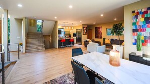 Amplia sala de estar con cocina, mesa de comedor y una escalera que lleva a otro nivel.
