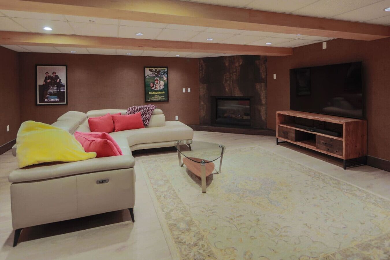 A modern living room with a sectional sofa, a coffee table, a flat-screen TV, and a fireplace.