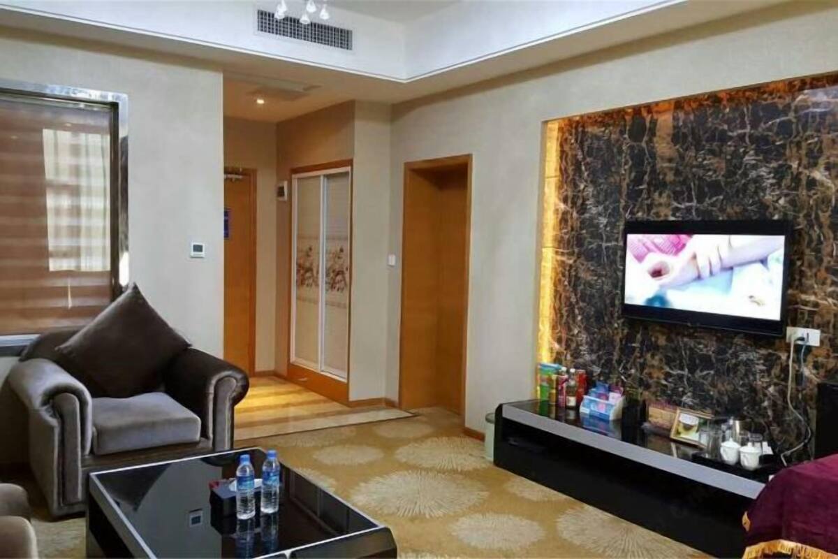 Een moderne woonkamer met een bank, een salontafel en een flatscreen televisie bevestigd aan een marmeren muur.