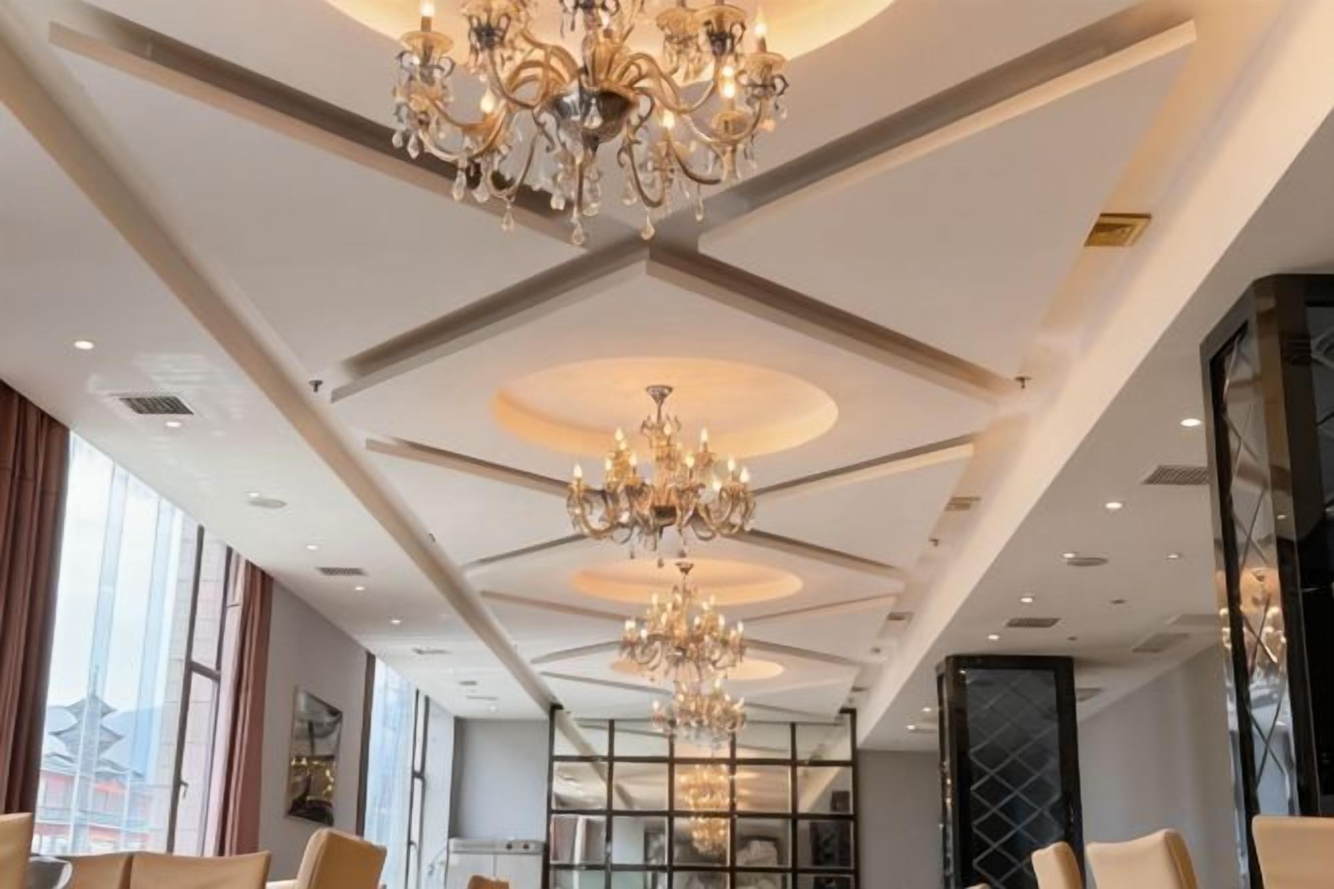 Un vestíbulo de hotel con candelabros, asientos y ventanas amplias.