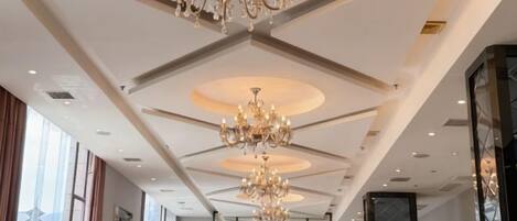 Un vestíbulo de hotel con candelabros, asientos y ventanas amplias.