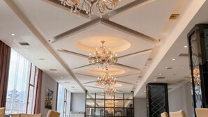 Een hotel lobby met kroonluchters, een glazen scheiding en zitgedeeltes.