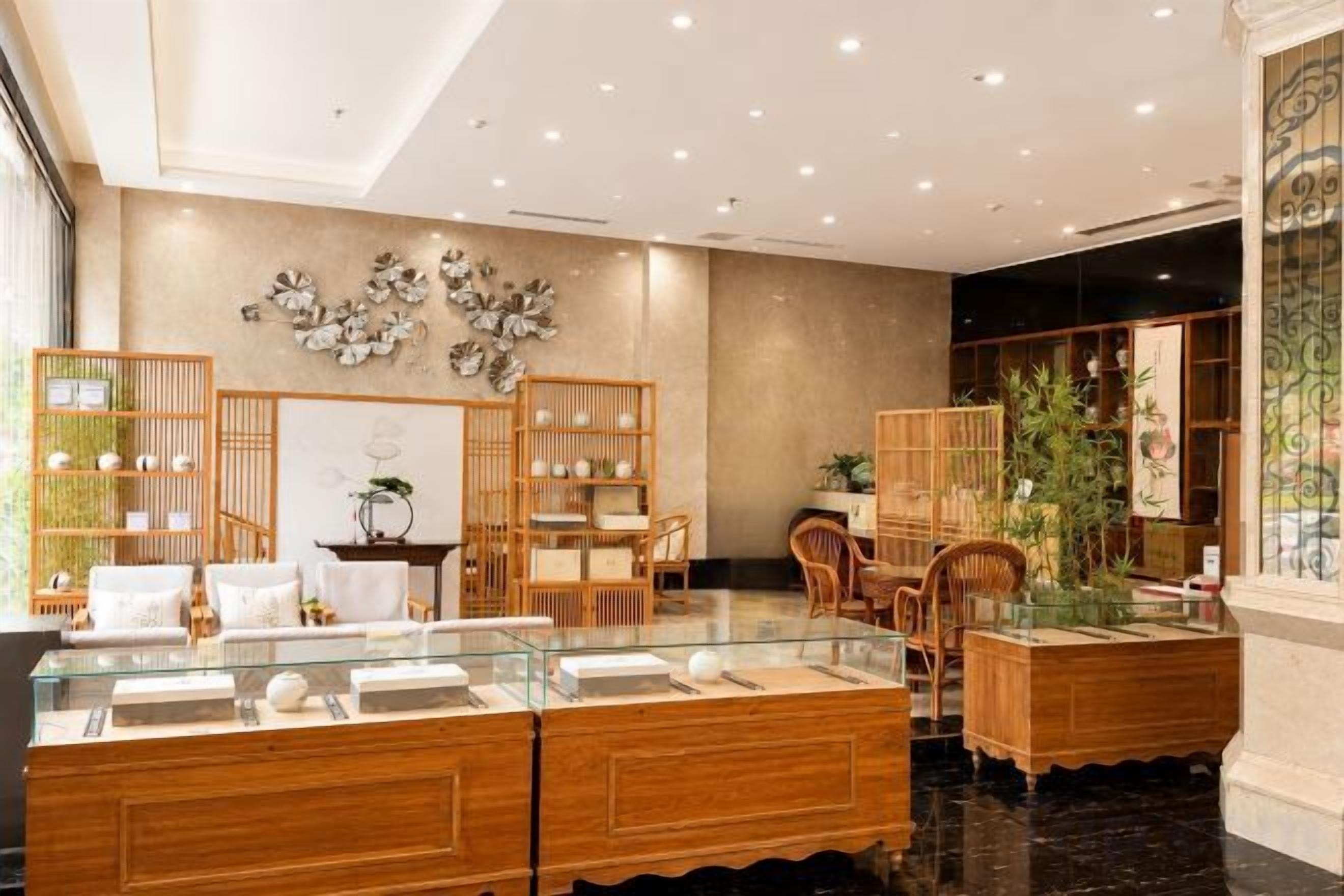 Un hall d’hôtel comprenant un comptoir d’accueil, un espace salon et des plantes décoratives.