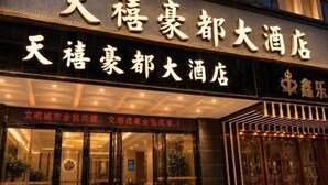 Een hotel ingang met een groot bord in Chinese karakters, een glazen deur en een decoratieve gevel.