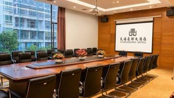 A conference room with a long table, chairs, and a projector screen displaying hotel branding.