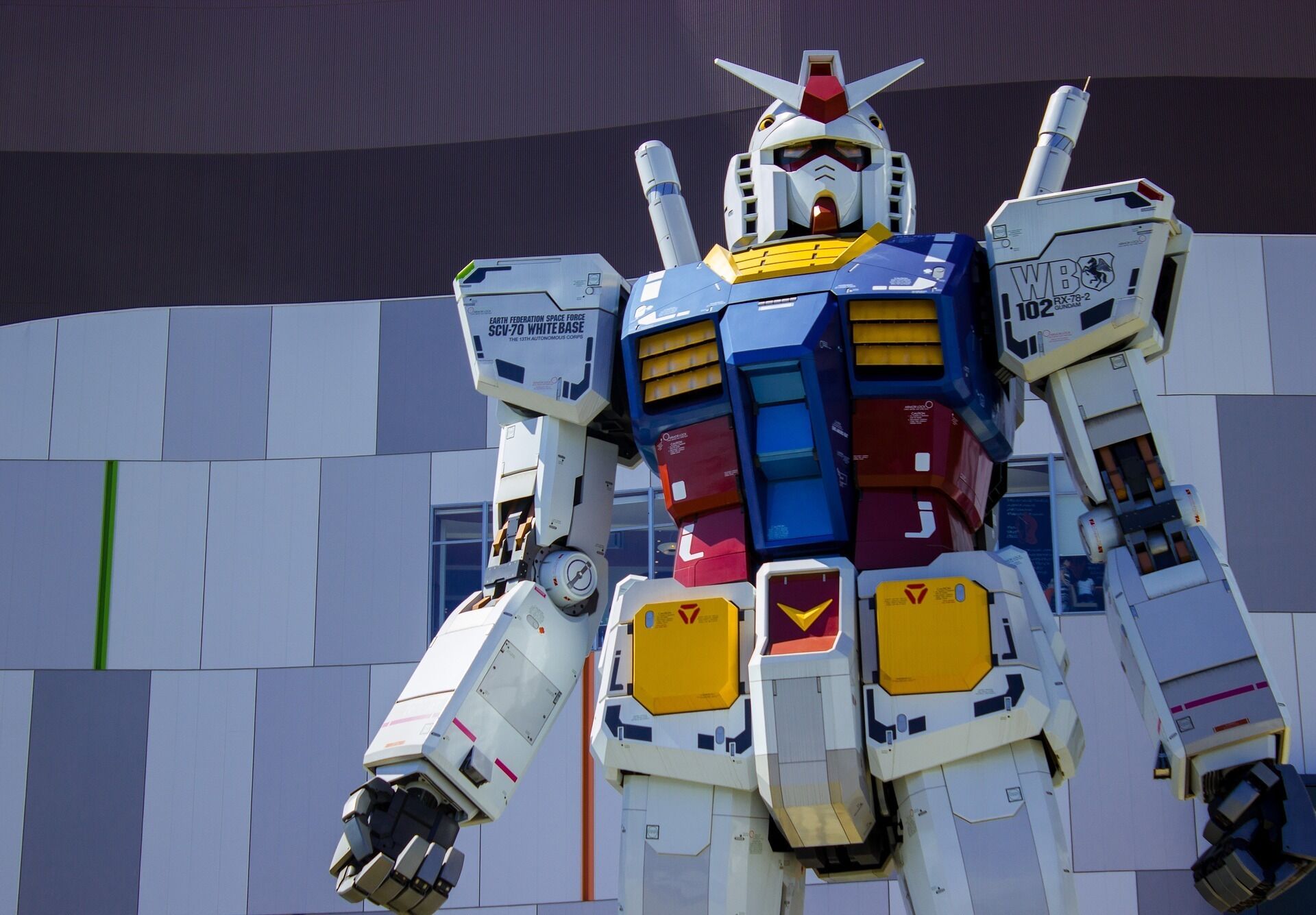 A large, colorful robot model with various mechanical parts and a complex design, set against a modern building facade.