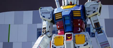 A large, colorful robot model with various mechanical parts and a complex design, set against a modern building facade.