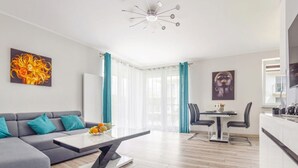 Un salon moderne avec un canapé d’angle gris, une table basse et un coin repas comprenant une table et des chaises.