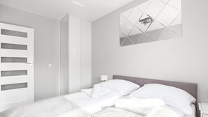 Une chambre à coucher moderne avec un lit, une armoire et un miroir au mur.