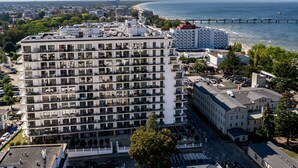 Een hotel met meerdere verdiepingen, met een modern architectonisch ontwerp, balkons en uitzicht op zee.