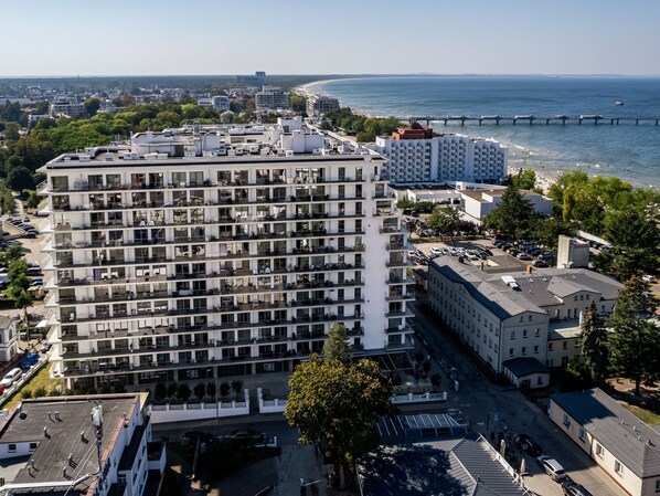 Ein mehrstöckiges Hotel mit moderner Architektur, mit Balkonen und Blick auf das Meer.