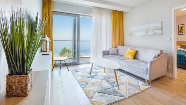 Een moderne woonkamer met een bank, salontafel en uitzicht op de zee door grote ramen.