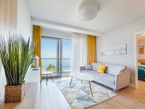 Ein modernes Wohnzimmer mit einer Couch, einem Couchtisch und Meerblick durch große Fenster.
