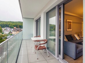Ein Balkon mit Tisch, Stühlen, einer Couch und Blick auf die Stadt.