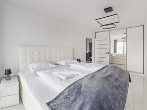 Ein modernes Schlafzimmer mit einem großen Bett, einem Nachttisch, einer Lampe und einem Kleiderschrank.