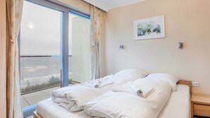 Een slaapkamer met een groot bed, uitzicht door een schuifdeur en een schilderij aan de muur.