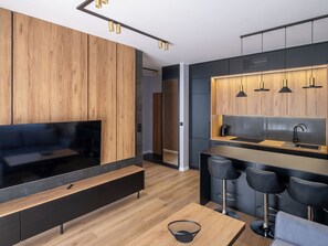 A modern kitchen with wooden cabinets, a black countertop, and a built-in stove.