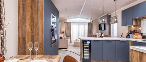 Une cuisine moderne dotée d’un îlot central, d’un coin repas avec une table pour deux personnes et d’un espace de vie avec un canapé.