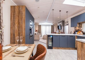 A modern kitchen with a central island, dining area with a table set for two, and a living space with a sofa. - Luxurious Lodge, perfect for couples or familes, sleeping four people. (Nr Kintore)