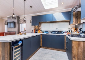 A modern kitchen with a central island, built-in appliances, and pendant lighting. - Luxurious Lodge, perfect for couples or familes, sleeping four people. (Nr Kintore)