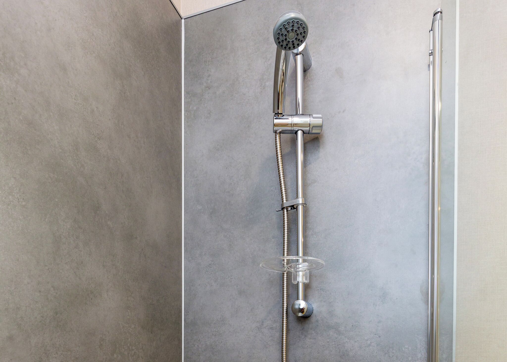 Une douche équipée d’un pommeau de douche à main, d’un flexible de douche et d’un tuyau flexible.