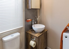 A bathroom with a white sink, wooden vanity, toilet paper holder, and a towel rack. - Luxurious Lodge, perfect for couples or familes, sleeping four people. (Nr Kintore)
