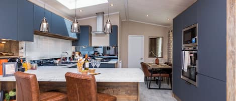 Una cucina moderna con isola centrale, sgabelli da bar, zona pranzo ed elettrodomestici integrati.