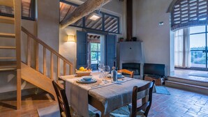 Un comedor con una mesa preparada para dos, una chimenea y una escalera que sube a un nivel superior.