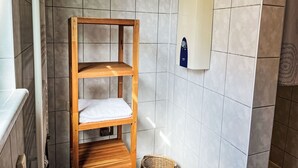 A bathroom with a wooden shelf unit, a towel rack, and a water heater. - Dat lütt Huus by Interhome (Zinnowitz)