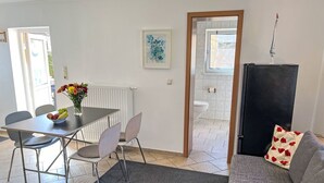 A modern living room with a grey sofa, a dining table with chairs, a black cabinet, and a flower vase. - Dat lütt Huus by Interhome (Zinnowitz)