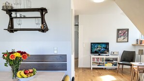 A modern living room with a dining area, wooden flooring, a TV, bookshelves, and a painting on the wall. - Dat Huus by Interhome (Zinnowitz)