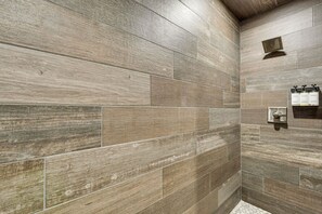 A shower area with wooden tiles and a wall-mounted soap dispenser.