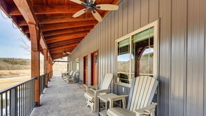 Un portico coperto con poltrone Adirondack, una ventola a soffitto e vista sul paesaggio desertico.