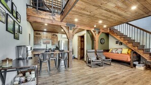 Un'ampia zona giorno in stile loft, con cucina, sala da pranzo e una scala che conduce a un livello superiore.