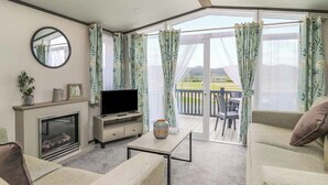 A living room with a fireplace, television, and a balcony with outdoor furniture. - 2 bedroom accommodation in Caersws (Caersws)