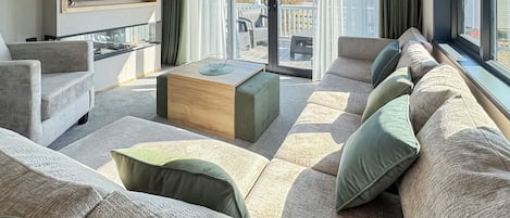 Una sala de estar moderna con un sofá seccional, una mesa de centro de madera y un ventanal con cortinas.