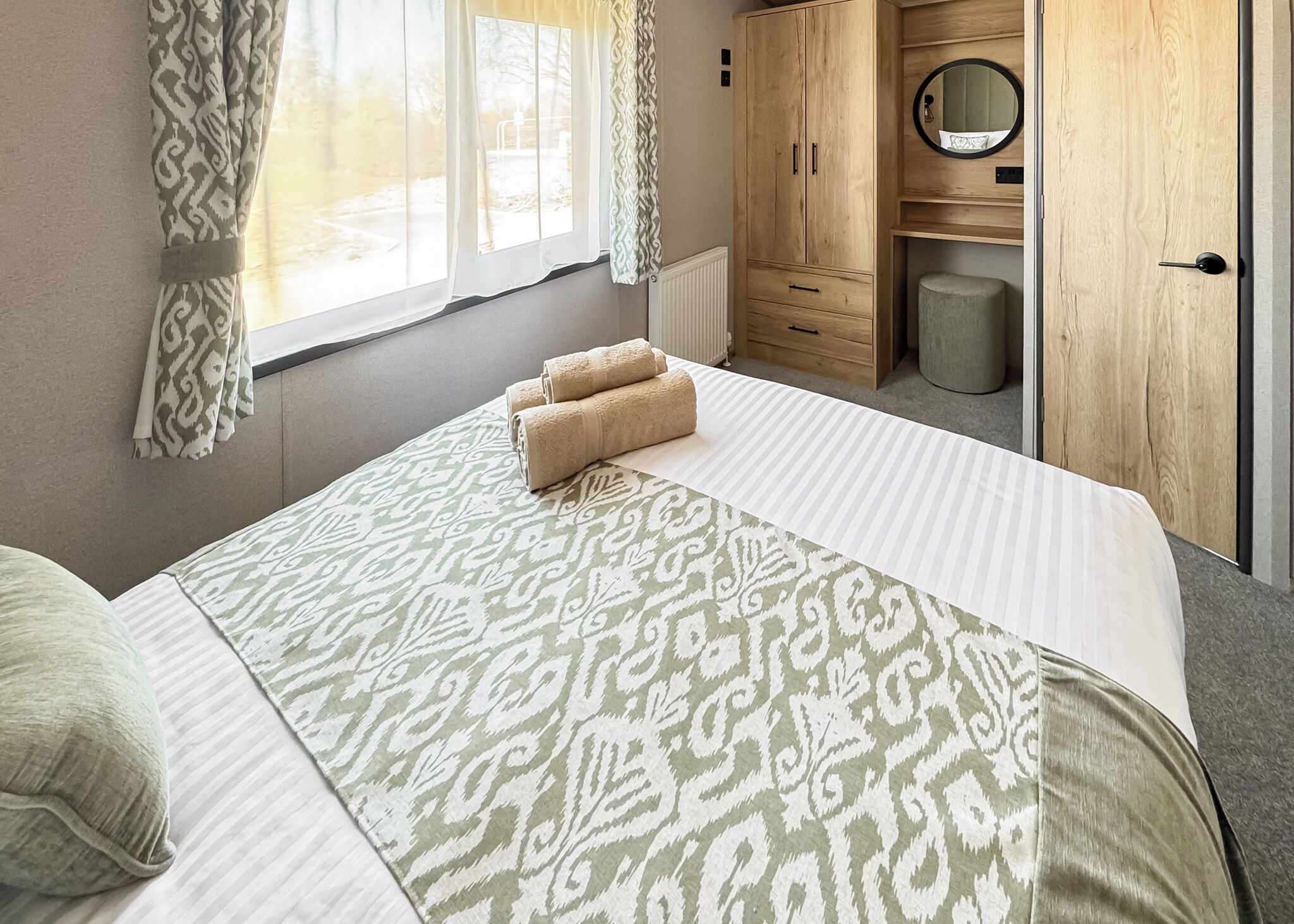 Une chambre à coucher avec un lit, une armoire, un miroir et une fenêtre.