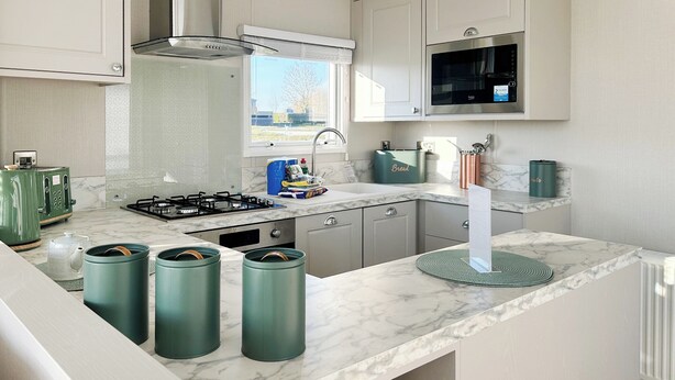 A modern kitchen with a gas stove, a microwave, and green storage containers.