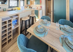 A modern kitchen with a wooden countertop, bar stools, and a dining table set for four.